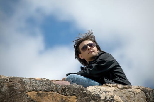 Young man sitting on a stone wall