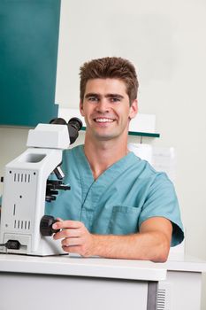 Portrait of happy male doctor with microscope