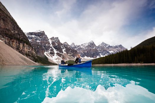 Man and woman sailing on peaceful lake against mountain range