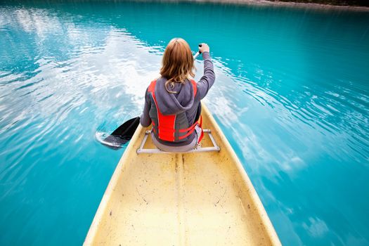 Rear view of woman rowing boat on calm water