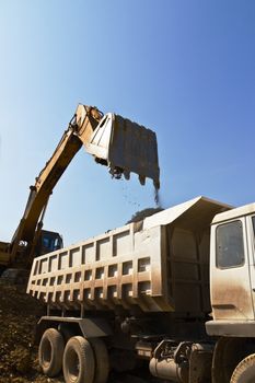 excavator loader and truck during earthmoving works outdoors  at the quarry