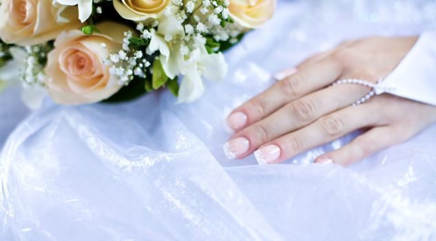 Bride's hand with golden ring and bouquet