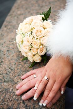 hands of new married with golden rings and bouquet