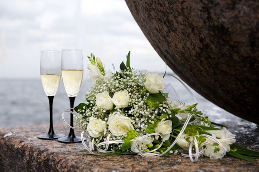 wedding bouquet and two champagne glasses outdoors