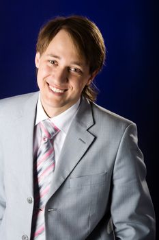 Young man wearing suit laughing over dark background