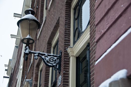 Snow covered street light at facade in Amsterdam, the Netherlands imn Winter
