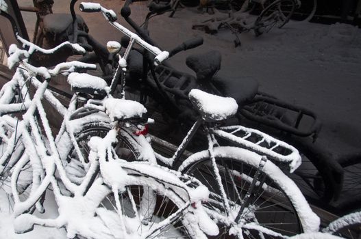 snow-covered bikes after a blizzard with reflections in black shopping window