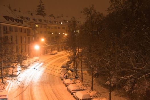 Main street covered with fresh snow and cars finding their way at night