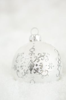 Pretty christmas bauble with silvery decorations lying in the snow