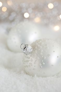 Pretty christmas baubles lying in fake snow in winterscene