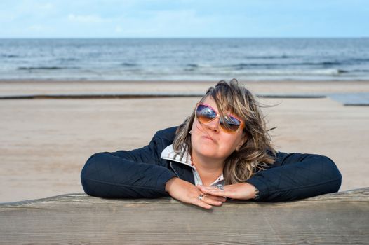 Portrait of mature woman in sunglasses relaxing at the Baltic sea in autumn day.