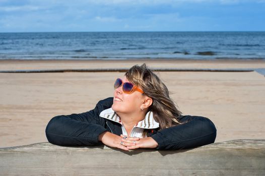 Portrait of mature woman in sunglasses relaxing at the Baltic sea in autumn day.