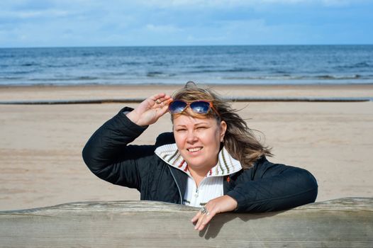 Portrait of mature woman in sunglasses relaxing at the Baltic sea in autumn day.