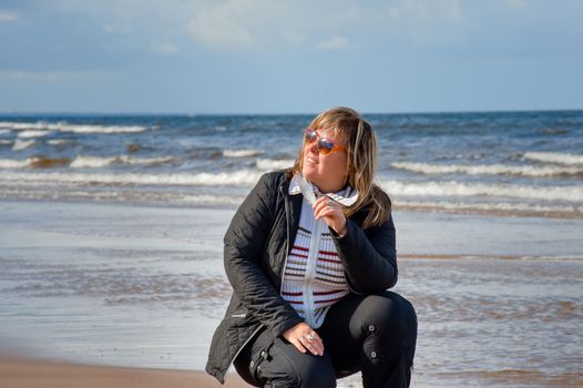 Mature chubby woman relaxing at the Baltic sea in autumn day.