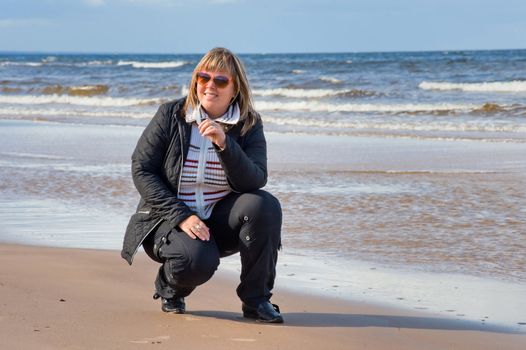 Mature chubby woman relaxing at the Baltic sea in autumn day.