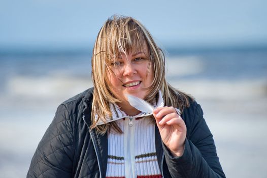 Portrait of mature chubby woman relaxing at the Baltic sea in autumn day.