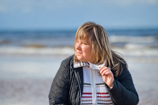 Portrait of mature chubby woman relaxing at the Baltic sea in autumn day.