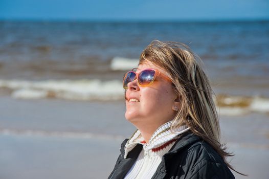 Portrait of mature woman in sunglasses relaxing at the Baltic sea in autumn day.