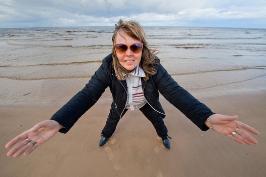 Mature funny attractive woman in sunglasses relaxing at the Baltic sea in autumn day.