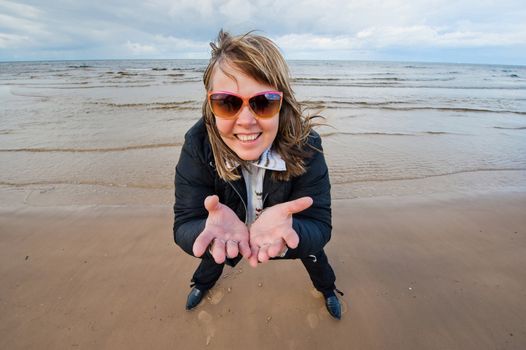 Mature funny attractive woman in sunglasses relaxing at the Baltic sea in autumn day.