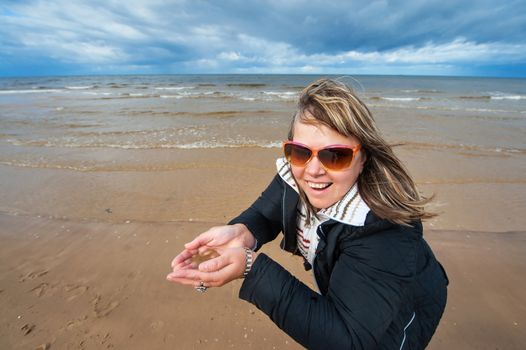 Portrait of mature funny attractive woman in sunglasses relaxing at the Baltic sea in autumn day.