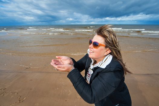 Mature attractive woman in sunglasses relaxing at the Baltic sea in autumn day.