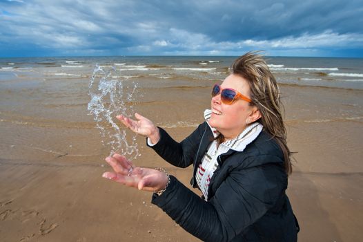 Mature attractive woman in sunglasses relaxing at the Baltic sea in autumn day.