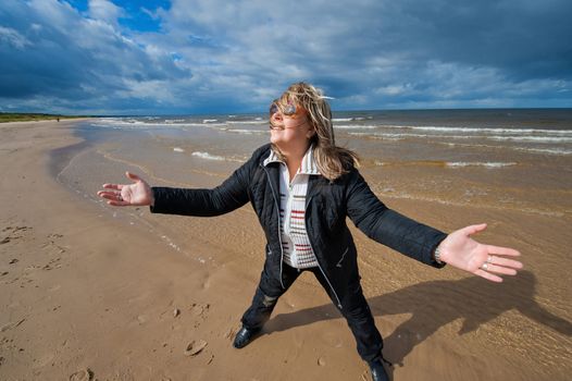 Mature funny attractive woman in sunglasses relaxing at the Baltic sea in autumn day.