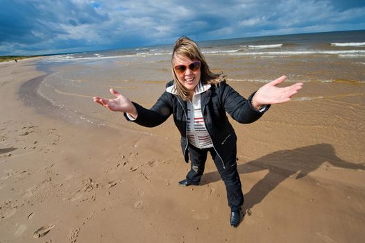 Mature funny attractive woman in sunglasses relaxing at the Baltic sea in autumn day.