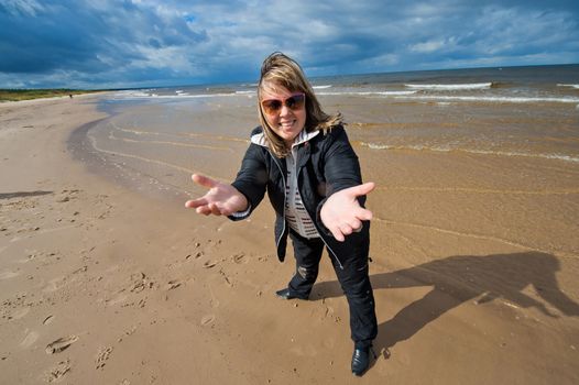 Mature funny attractive woman in sunglasses relaxing at the Baltic sea in autumn day.