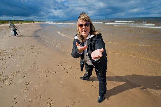 Mature funny attractive woman in sunglasses relaxing at the Baltic sea in autumn day.