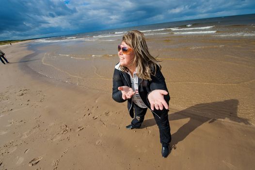 Mature funny attractive woman in sunglasses relaxing at the Baltic sea in autumn day.