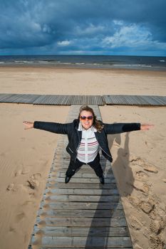 Mature funny attractive woman in sunglasses relaxing at the Baltic sea in autumn day.