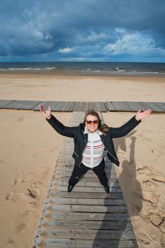 Mature funny attractive woman in sunglasses relaxing at the Baltic sea in autumn day.