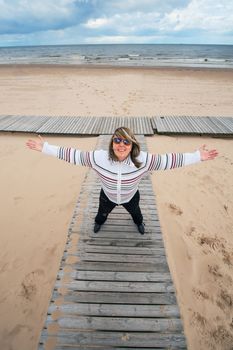 Mature funny attractive woman in sunglasses relaxing at the Baltic sea in autumn day.