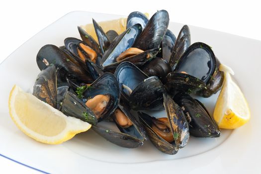 cooked mussels on a plate with lemon isolated on white with clipping path