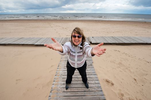 Mature funny attractive woman in sunglasses relaxing at the Baltic sea in autumn day.