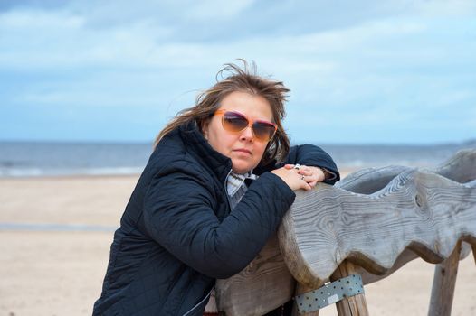 Mature woman in sunglasses relaxing at the Baltic sea in autumn day.