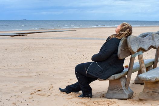 Mature woman relaxing at the Baltic sea in autumn day.