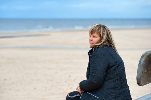 Mature woman relaxing at the Baltic sea in autumn day.