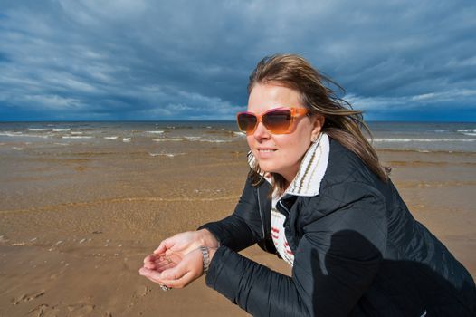 Portrait of mature attractive woman in sunglasses relaxing at the Baltic sea in autumn day.