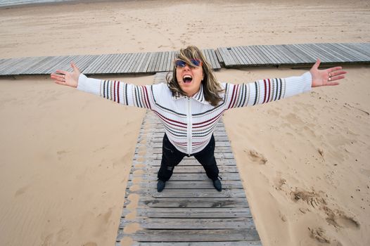 Mature funny attractive woman in sunglasses relaxing at the Baltic sea in autumn day.