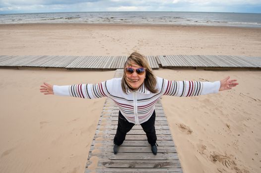 Mature funny attractive woman in sunglasses relaxing at the Baltic sea in autumn day.