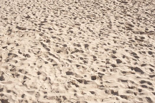 Texture of a sandy beach full of footprints