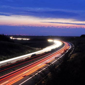 night traffic on busy highway with cars lights and blue sky