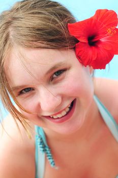 Portrait of a young girl on tropical beach with red flower