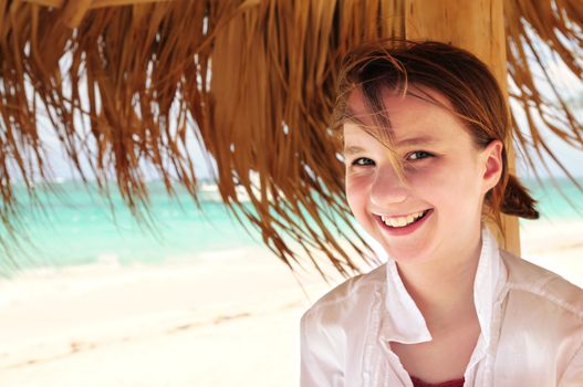 Portrait of a young girl on tropical beach under umbrella