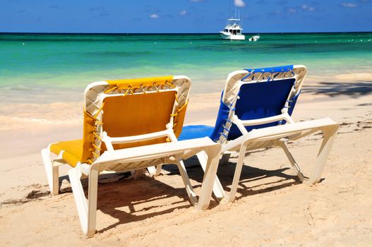 Two vacation chairs on sandy tropical beach of Caribbean island