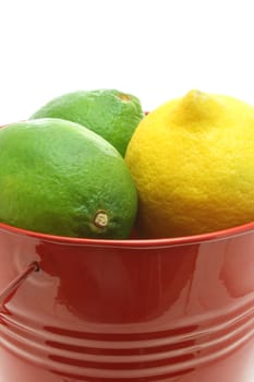 A red bucket of citrus fruit isolated on a white background.