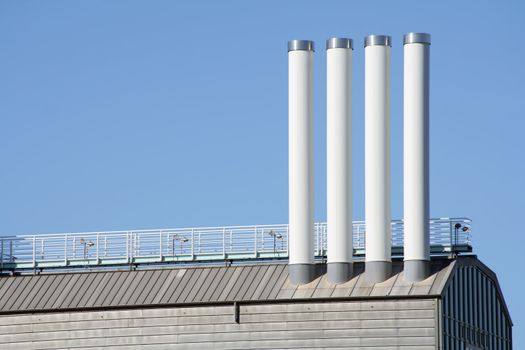 Four chimneys on the roof of a modern corporate building, which is supposed to look like a ship, being located in the harbour of Hamburg/Germany. Clear blue sky. Copy space.